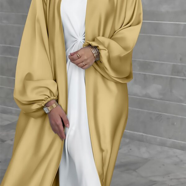 Model wearing Newness's Serene Sands Satin Abaya, a flowing maxi dress in luxurious satin fabric. The abaya is elegantly styled and perfect for any occasion.