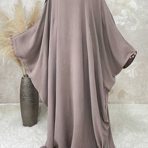Desert Bloom Batwing Abaya in a flattering pose on a model, highlighting its flowing fabric and elegant design.