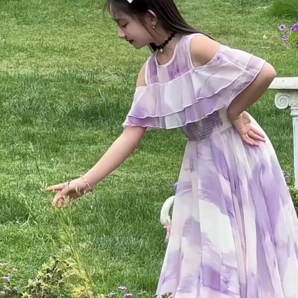 Adorable girl twirling in a flowy, elegant chiffon dress, perfect for summer. The dress is in a beautiful summer garden setting.