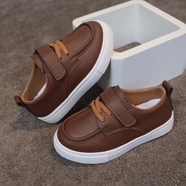 Close-up of stylish brown leather boys loafers, showcasing the stitching and buckle detail.