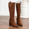 Newnesss commanding chunky heel knee high boots in brown leather showcasing the side profile and heel