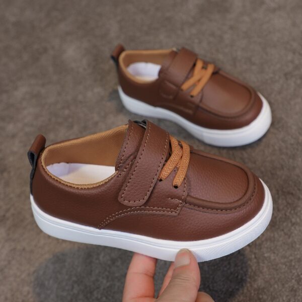 Close-up of stylish brown leather boys loafers, showcasing the stitching and buckle detail.