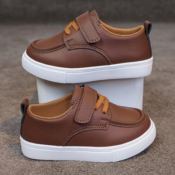 Close-up of stylish brown leather boys loafers, showcasing the stitching and buckle detail.