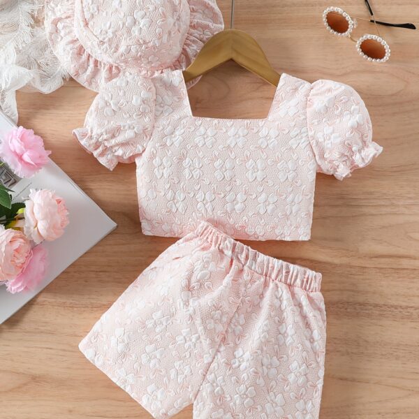 Adorable baby girl wearing a Summer Bloom floral outfit, perfect for summer. The outfit features a delightful floral pattern.
