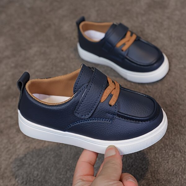 Close-up of stylish brown leather boys loafers, showcasing the stitching and buckle detail.