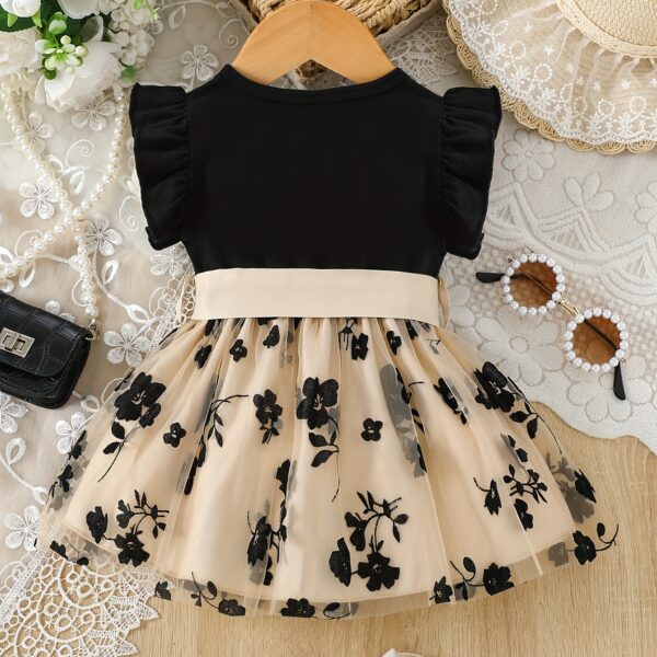 Adorable little girl twirling in a beautiful summer floral mesh dress from Newness. The dress is lightweight and perfect for warm weather.