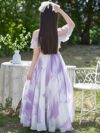 Adorable girl twirling in a flowy elegant chiffon dress perfect for summer The dress is in a beautiful summer garden setting